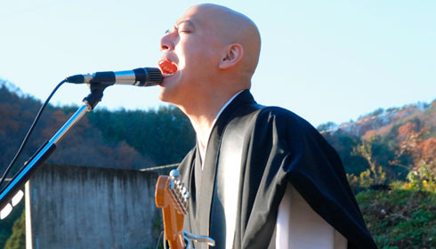 Japanese monk plays electric guitar and sings.