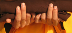 [close-up of a novice monk's hands holding robes]