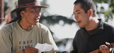 two men, one with Free Tibet on shirt, sit singing